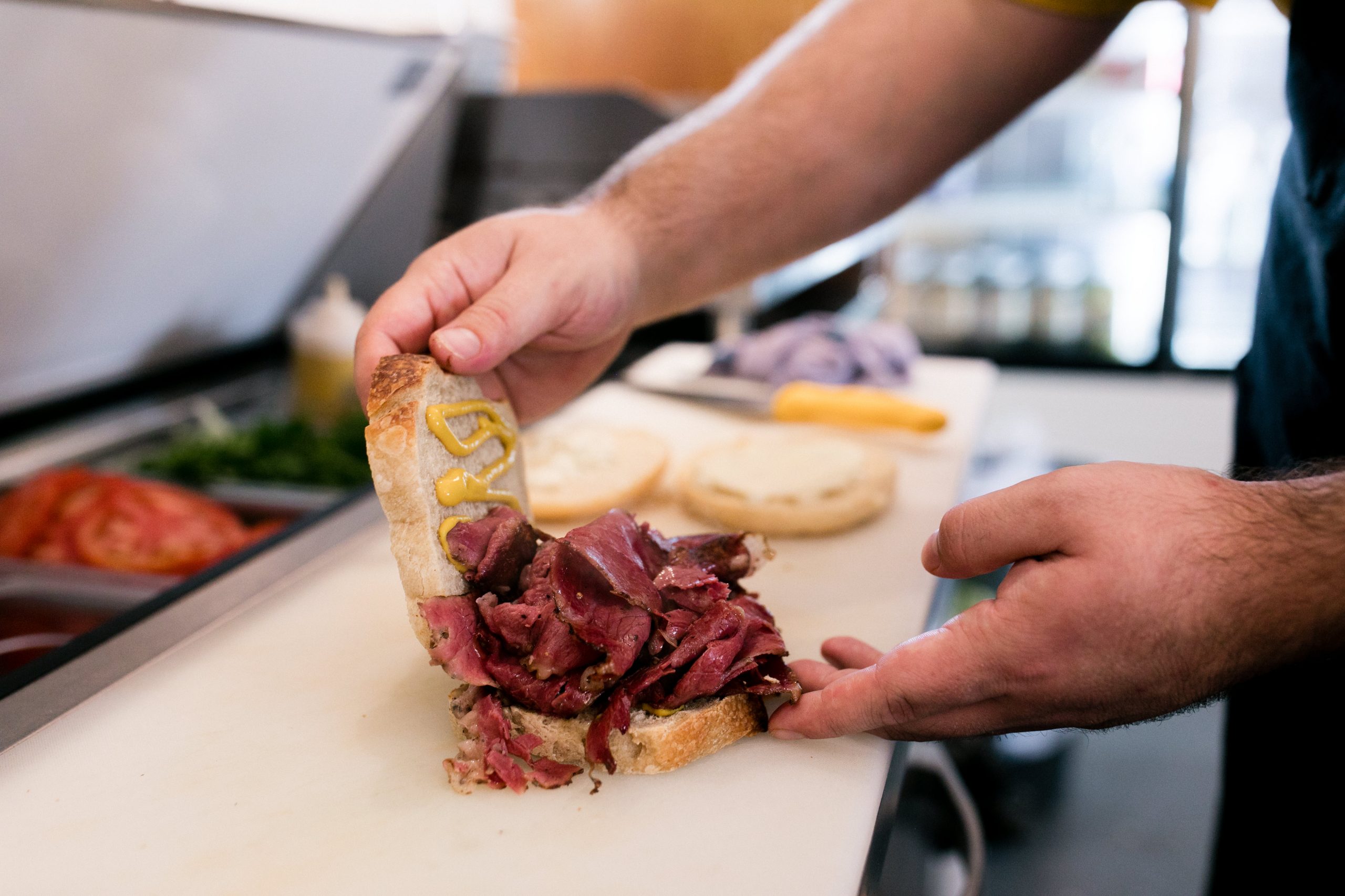 Two hands creating a deli sandwich