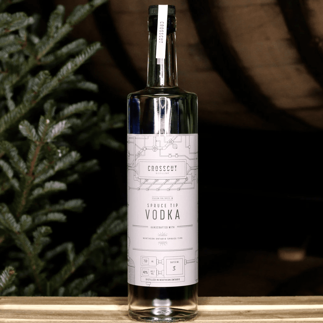 bottle of spruce tip vodka in front of spruce tree