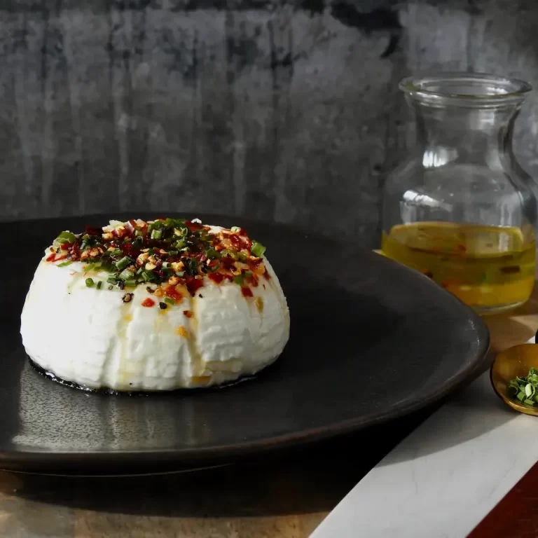 pecorino fresco on a black plate with bottle of olive oil in the background